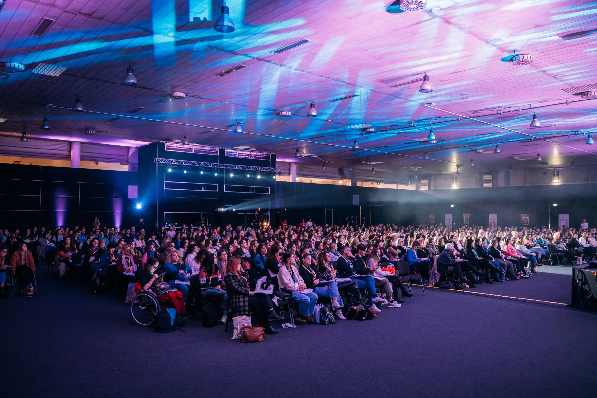 Packed audience under purple and blue light beams